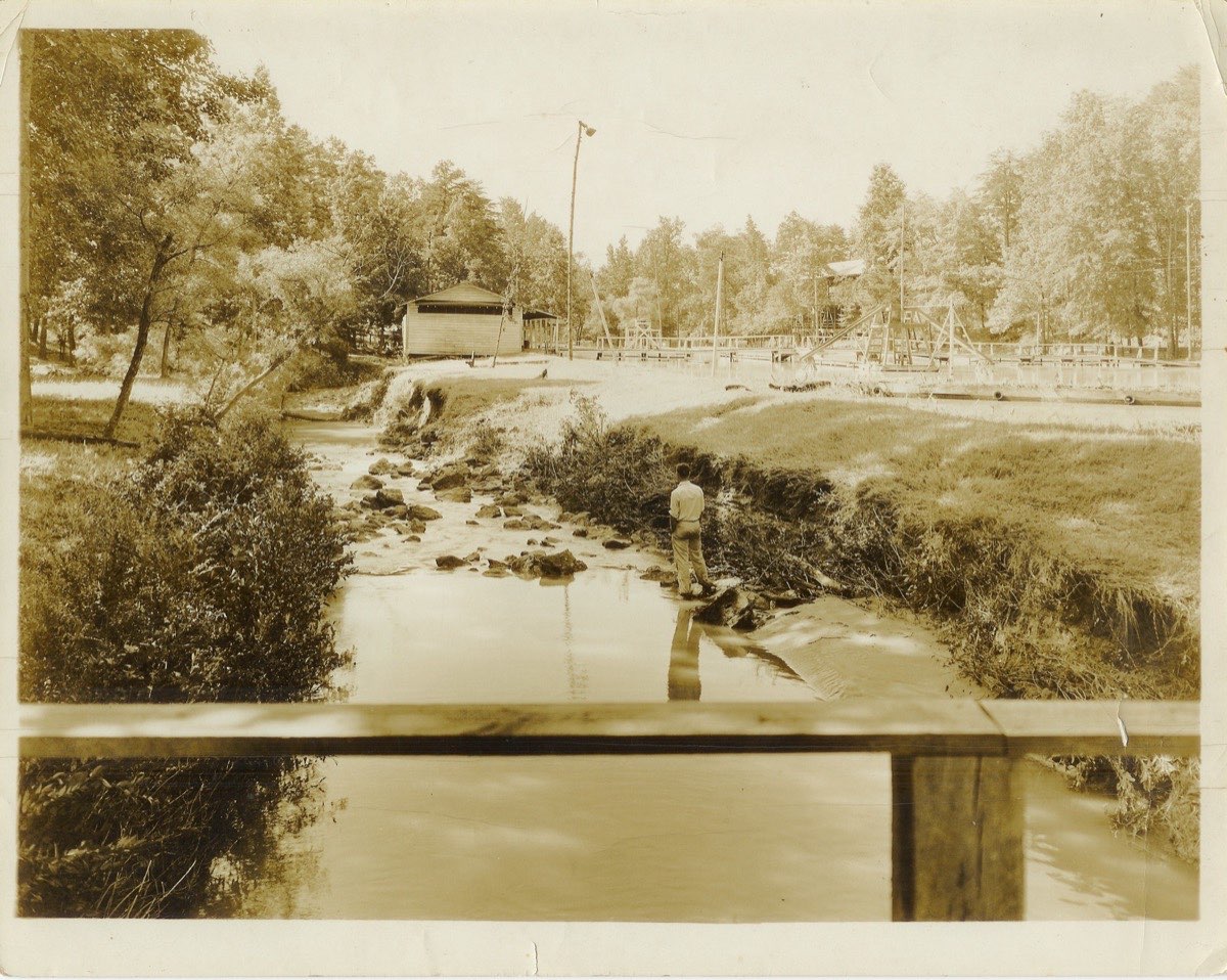 Lick Creek running through the Chick Springs Amusement Park with a man standing in the stream, c. 1928–1932